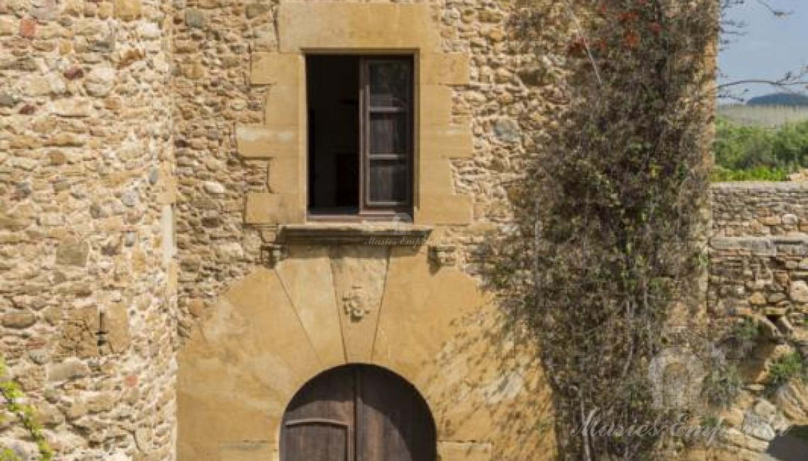 Detalle de la entrada principal de la Masía con arco en piedra tallada 