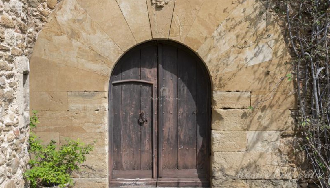 Detalle de la puerta principal de acceso a la masía con este magnífico arco de piedra tallada 