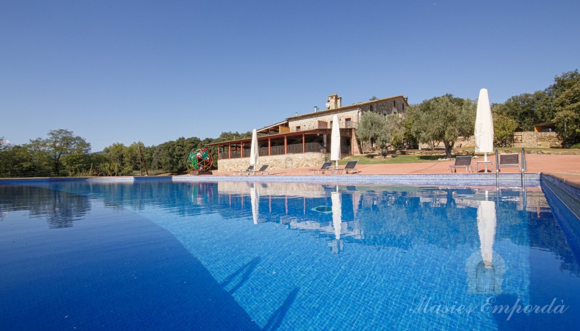 Vistes de la zona de piscina amb la masia el fons de la imatge