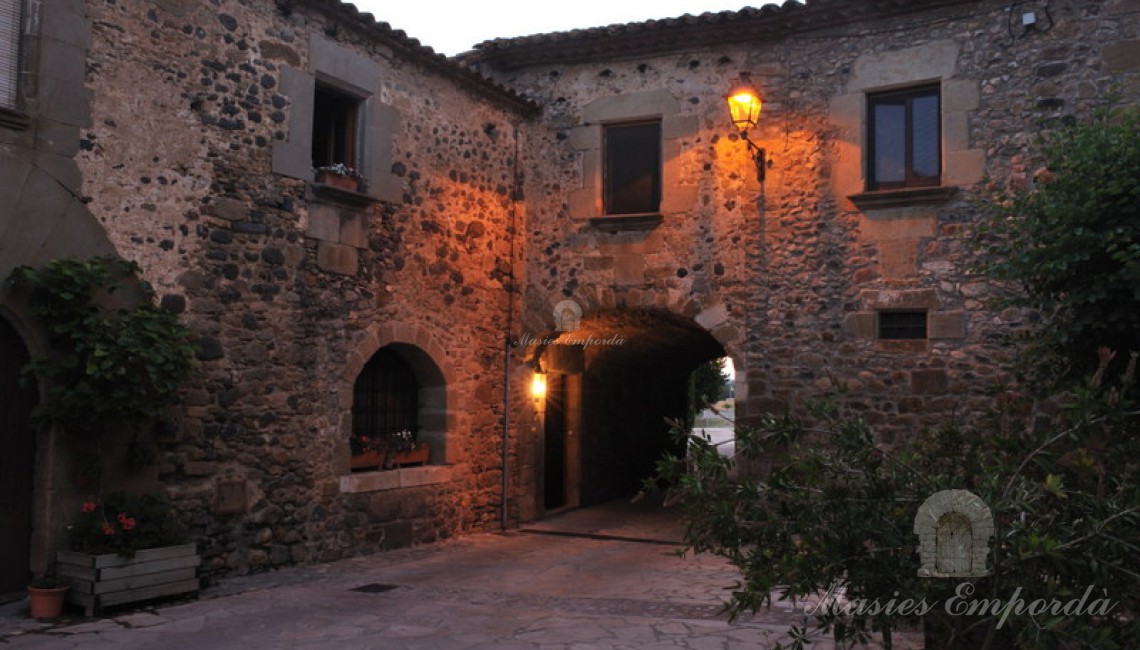 Fachada de la casa con la entrada a través de arcada de medio punto en piedra 