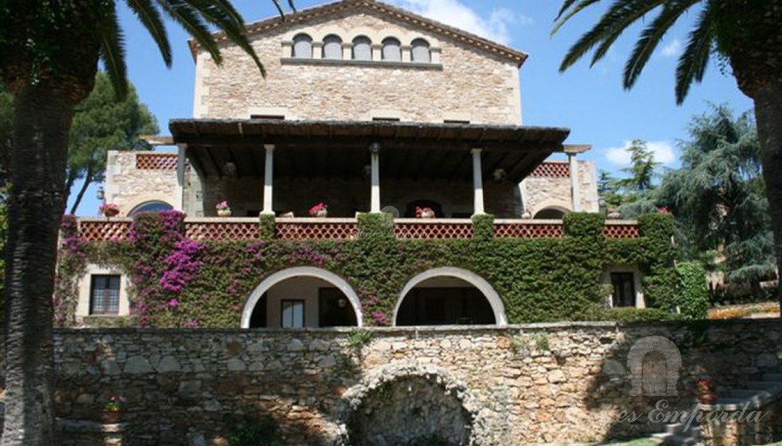Fachada sur de la Masía donde destacan los porches abovedaos de la casa y la gran terraza con vistas al jardín y al mar.    