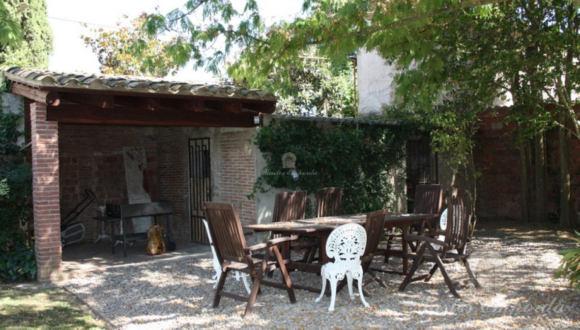Detalle de la barbacoa con porche cubierto en el jardín