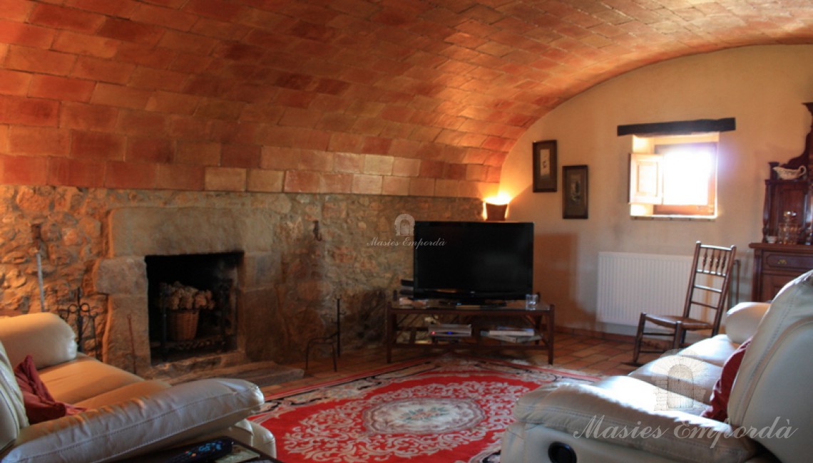 Salón de estar de la masía con chimenea con techos abovedaos Salón de estar de la masía con chimenea con techos abovedaos