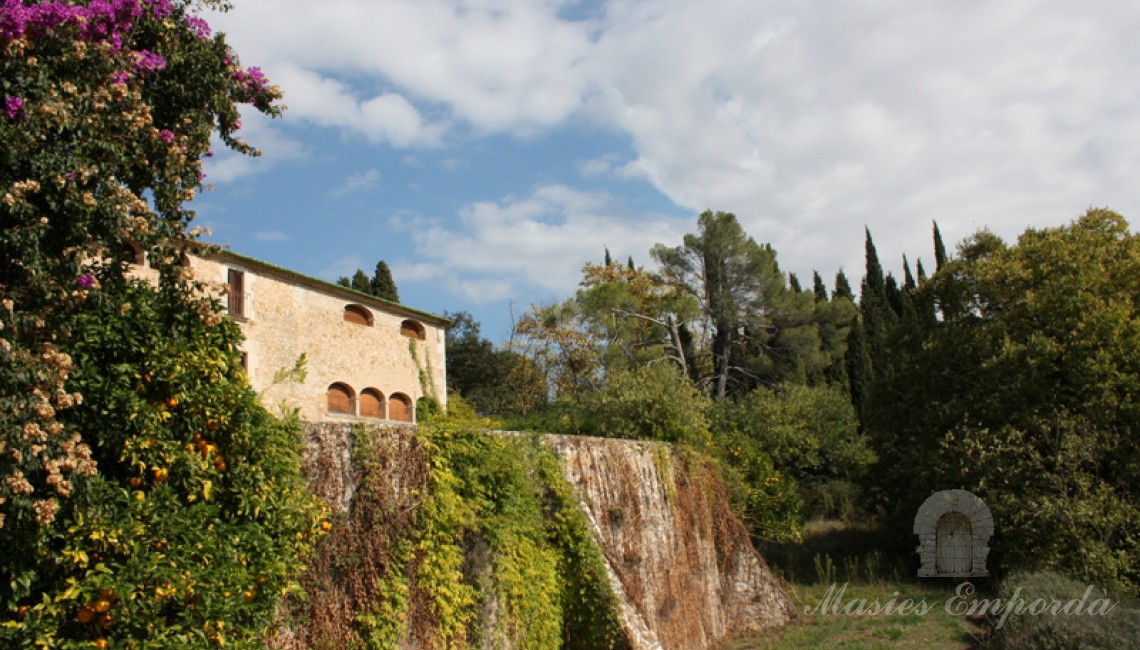 Muralla con contrafuertes parte sur de la masía que cobija en su interior parte del jardín que rodea la casa  