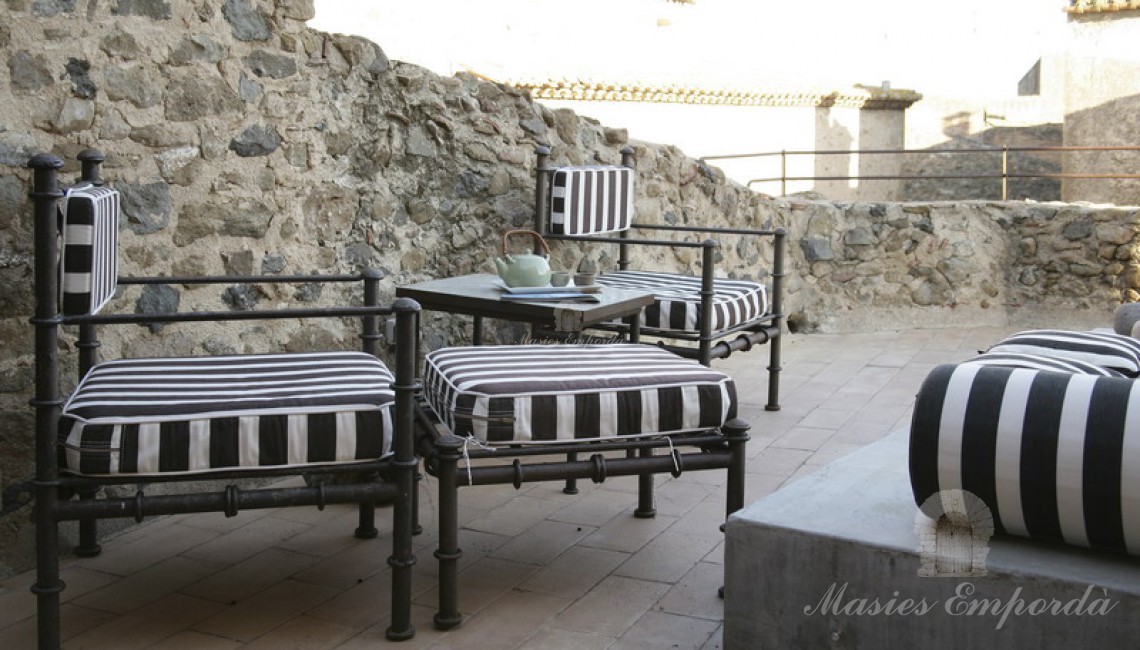 Terraza de la tercera planta de la vivienda con sillones de forja tapizados en tejido a rallas de color negro y blanco. 