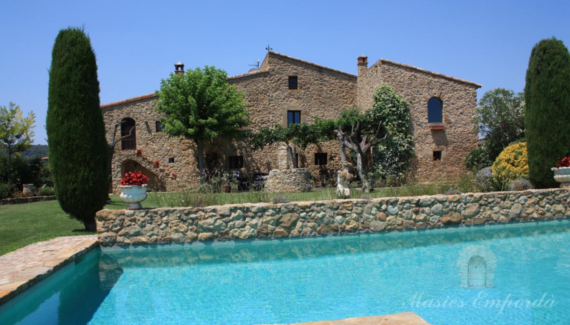 Vista de la fachada del conjunto de construcción de la masía parte del jardín y en primer plano la piscina Vista de la fachada del conjunto de construcción de la masía parte del jardín y en primer plano la piscina