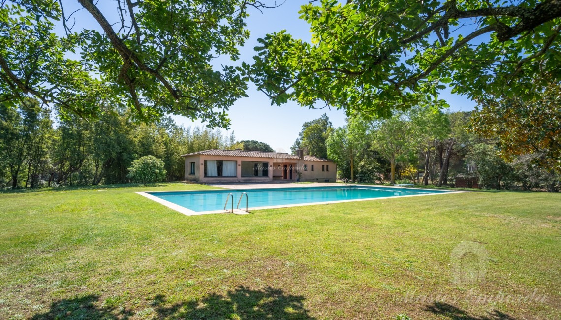 Vistes de la zona de piscina amb al pavelló al fons