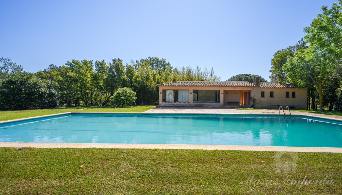 Vistes de la zona de piscina amb al pavelló al fons
