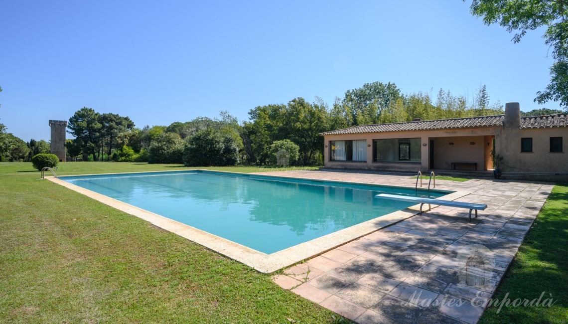 Vistes de la zona de piscina amb al pavelló al fons