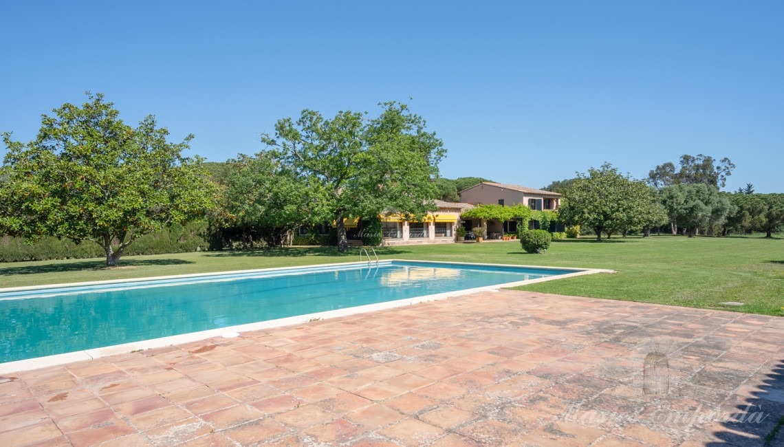 Vistes de la zona de piscina amb al pavelló al fons