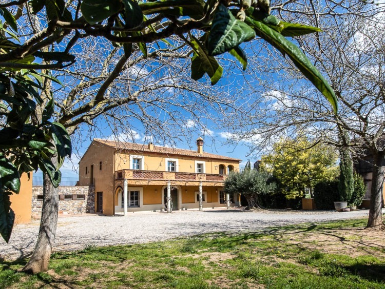 Vista de la façana de la masia i el jardí