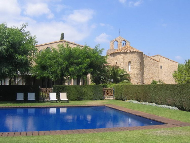 Vista desde el jardín de la piscina y de la casa al fondo de la imagen 