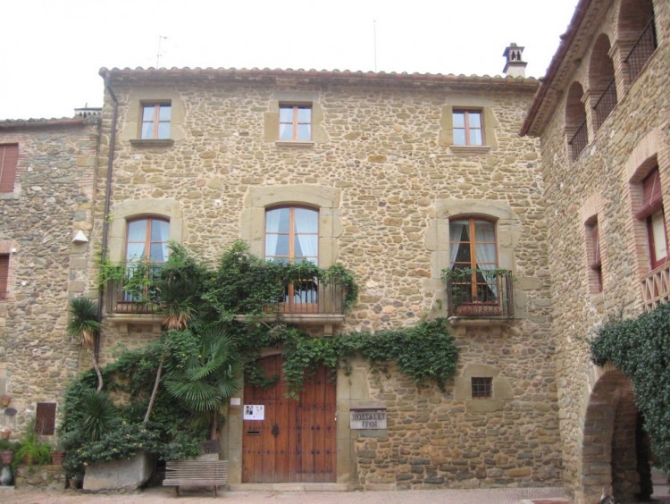 Fachada de la casa toda de piedra con portalón de entrada en madera 