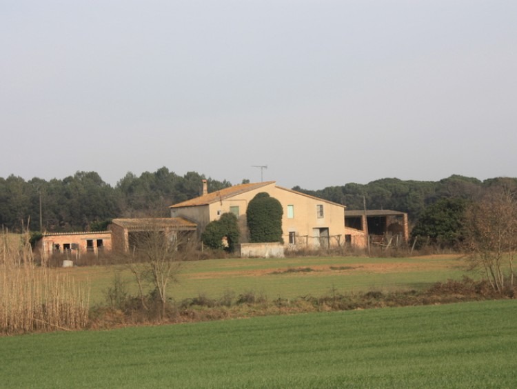 Vista del conjunto de la masía y los anexos rodeada de los campos de la propiedad 