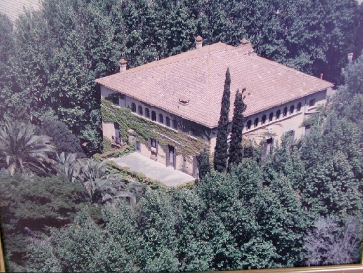 Vista aérea de la construcción rodeada de arboledas y jardines de la propiedad. 
