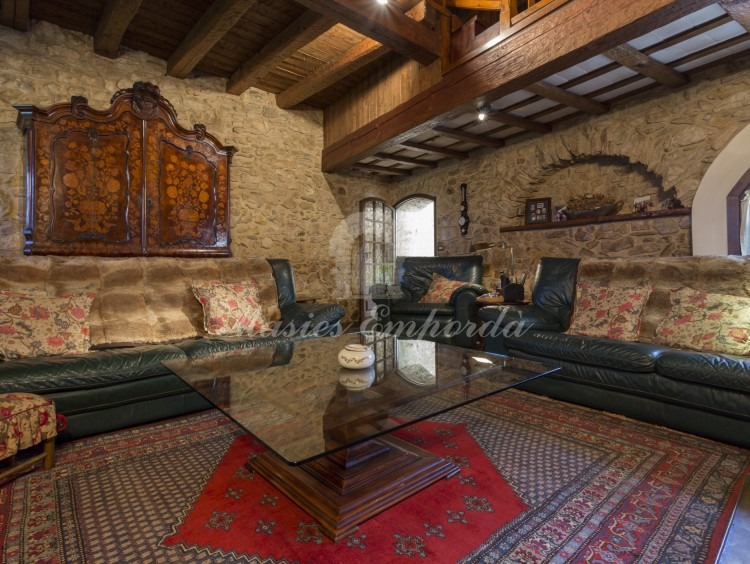 Saló d'estar amb llar de foc oberta, amb dos altura, on es troba la biblioteca a la part superior d'aquest.