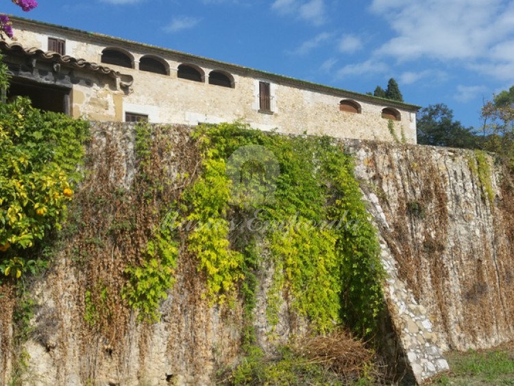 Muralla con contrafuertes parte sur de la masía que cobija en su interior parte del jardín que rodea la casa  