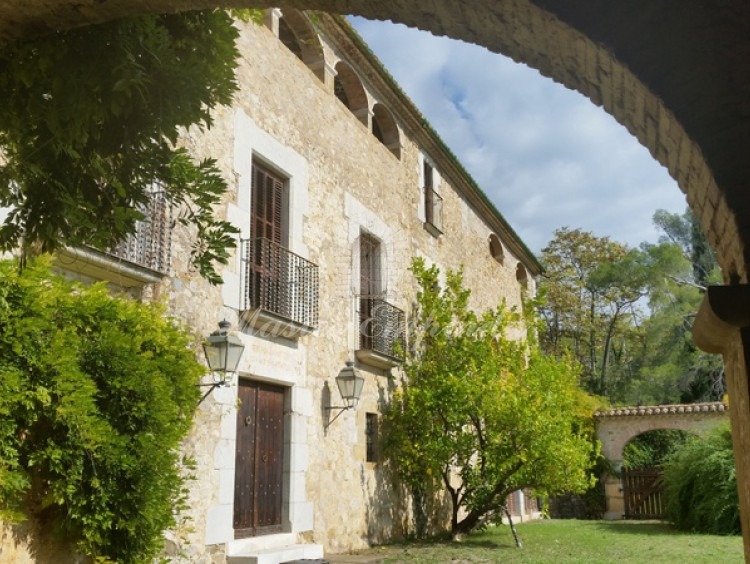 Detalle de la fachada d la masía desde el porche anexo a esta con vista del arco de medio punto que la enmarca