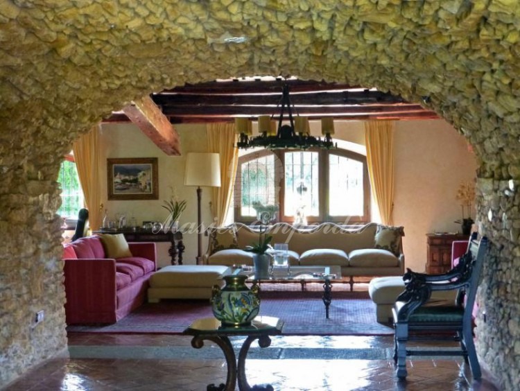 Salón abovedado en piedra que desemboca en el gran salón de la casa con vistas al jardín