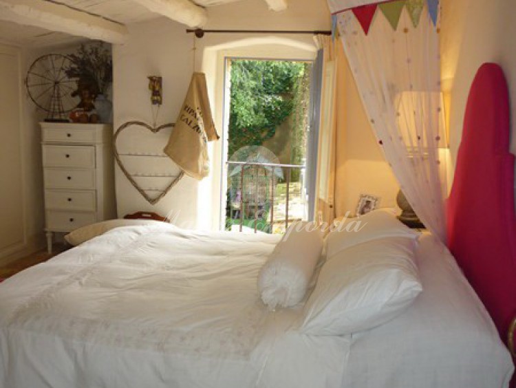 Una de las habitaciones dobles con cama con mosquitera colgada de las vigas de madera de la cubierta con ventanal con vistas a los campos cercanos. 