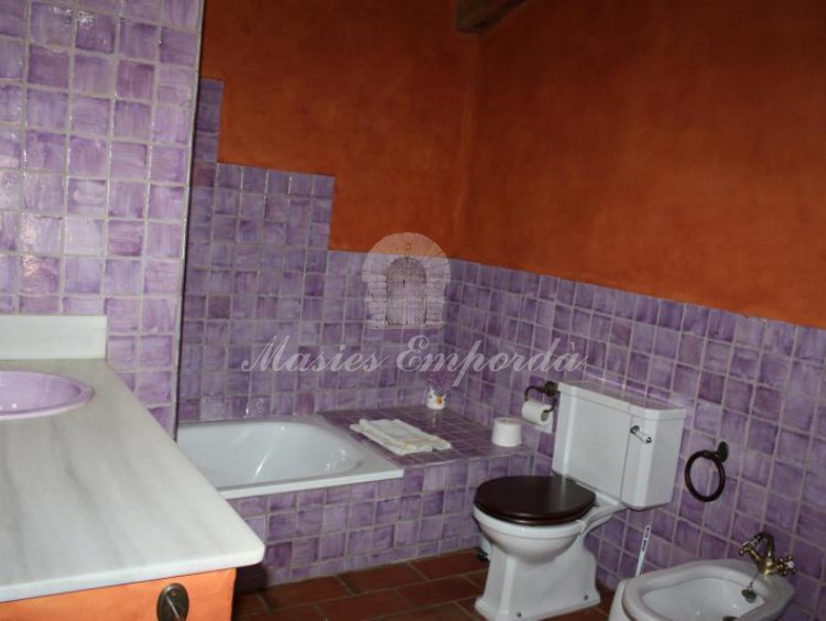 Baño completo de la suite con una cama y balcón al jardín 
