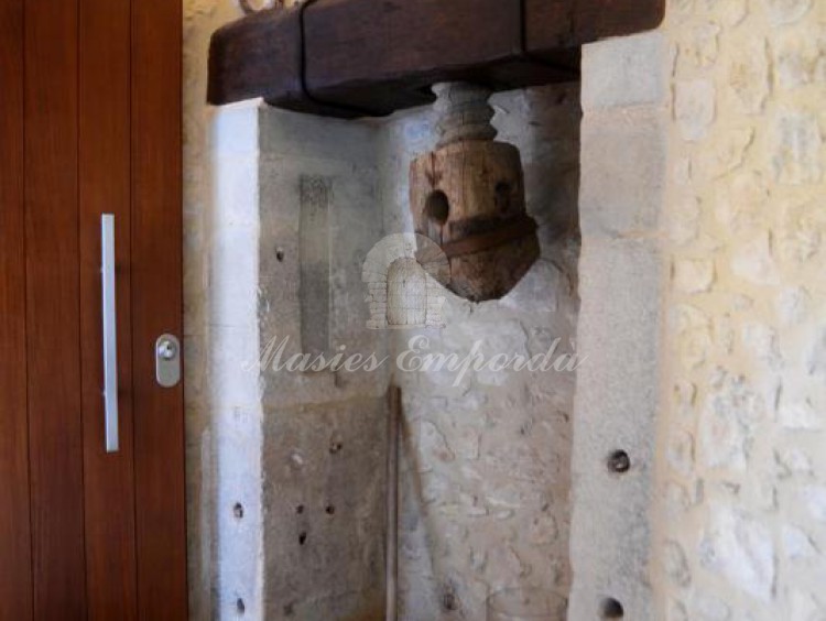 Detalle de la entrada a la casa con la prensa de tornillo de un antiguo molino de aceite 