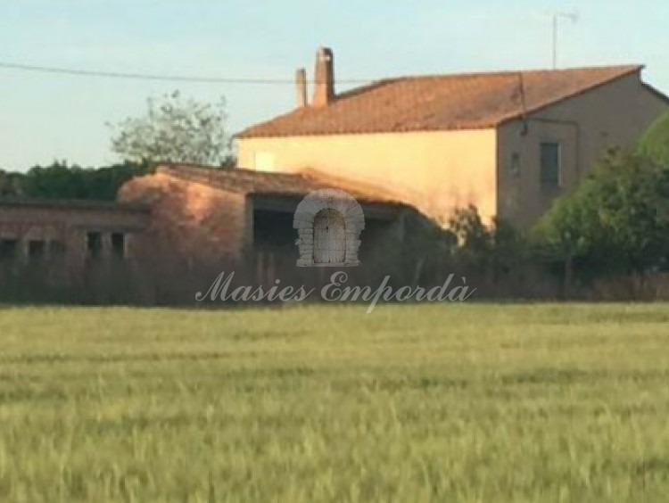 Vista lateral de la masía y los anexos con los campos de la propiedad 