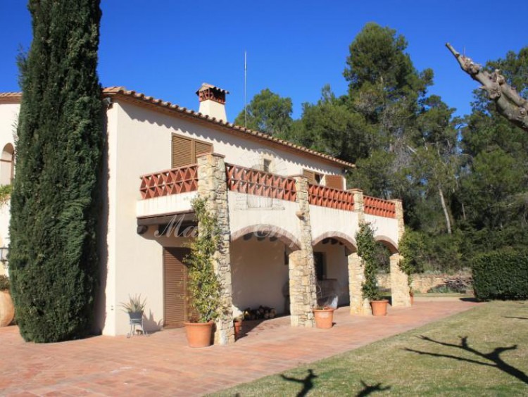Porche lateral de la casa con terraza en la segunda planta que contrasta con el azul del cielo del Baix Empordà