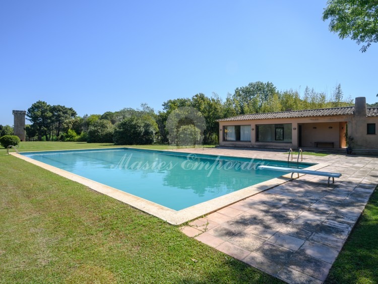Vistes de la zona de piscina amb al pavelló al fons